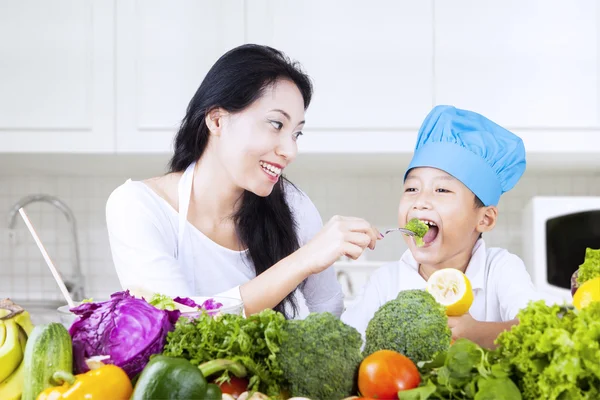 Mother feed brocolli to her child — Stock Photo, Image