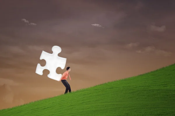 Podnikatel nést puzzle na strmém kopci — Stock fotografie