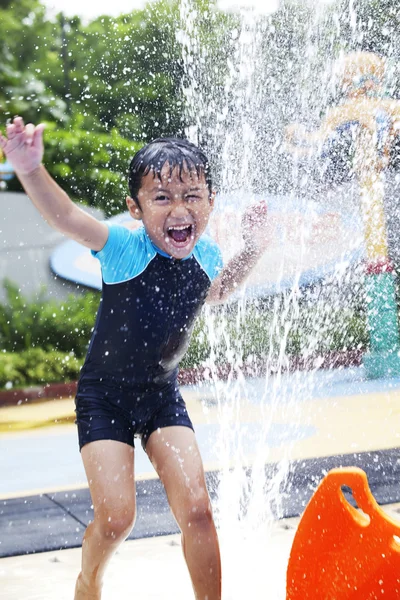 Menino feliz jogar água no parque aquático — Fotografia de Stock