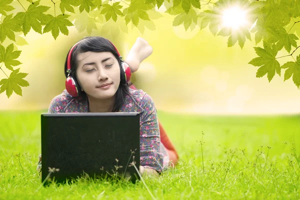 Chica joven escuchando música en la hierba — Foto de Stock