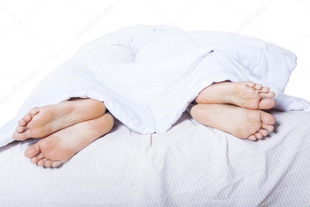 Close-up of feet apart on bed