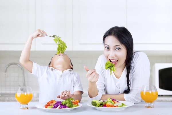 Mãe e menino comendo salada em casa — Fotografia de Stock