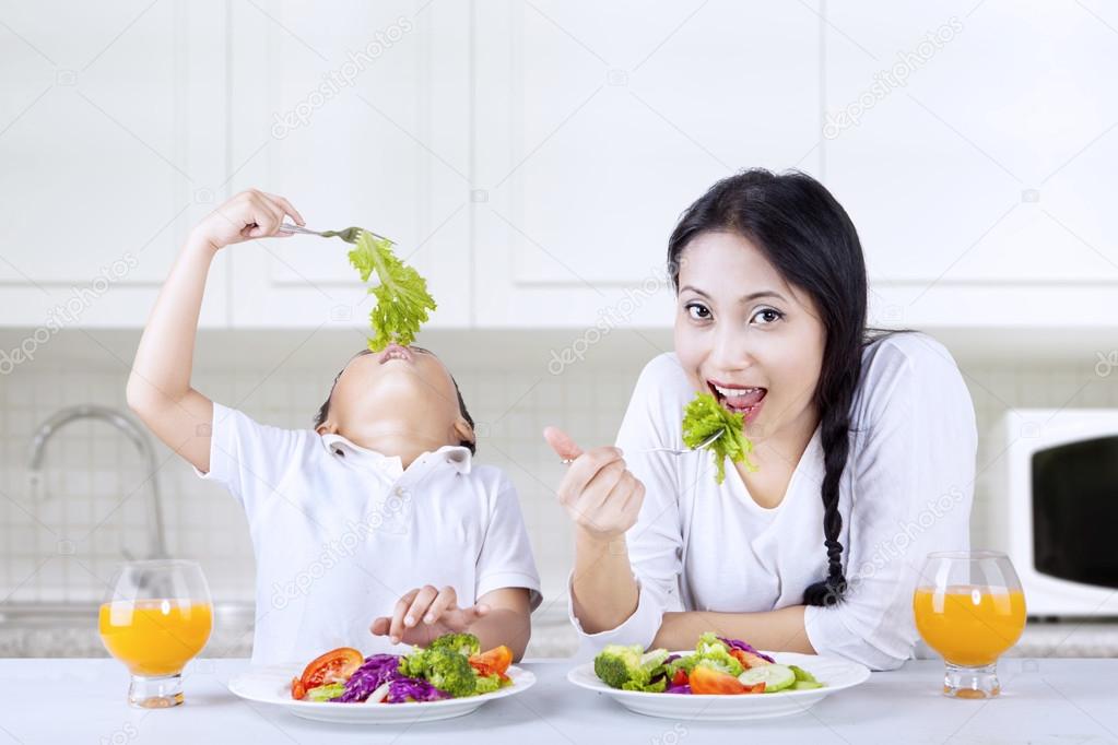 Mother and boy eating salad at home