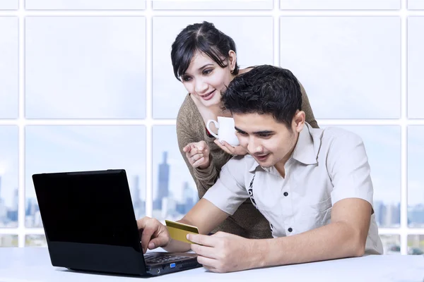 Азиатская пара, платящая онлайн в офисе с помощью кредитной карты — стоковое фото