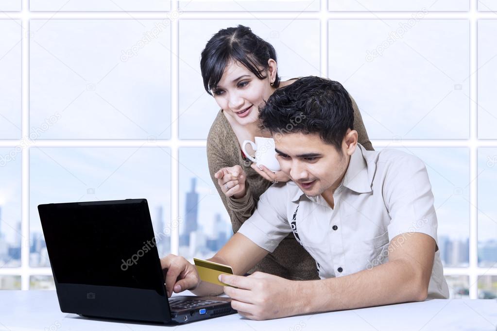 Asian couple paying online in office using credit card
