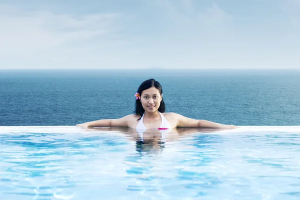 Mujer asiática relajándose en la piscina de lujo junto a la playa — Foto de Stock