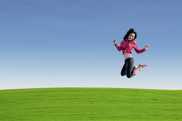 Asiatico donna jumping oltre verde campo — Foto Stock