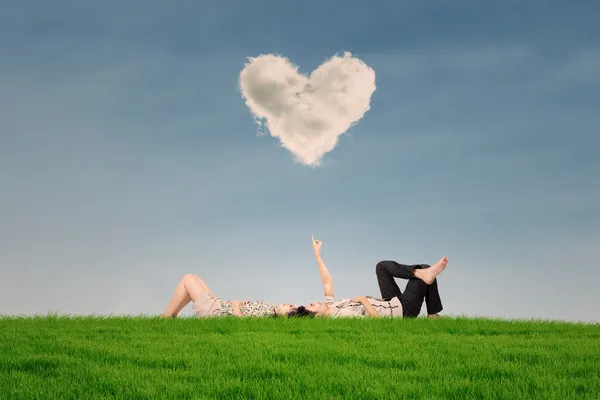 Pareja disfrutar de vacaciones bajo la nube de corazón en el parque — Foto de Stock