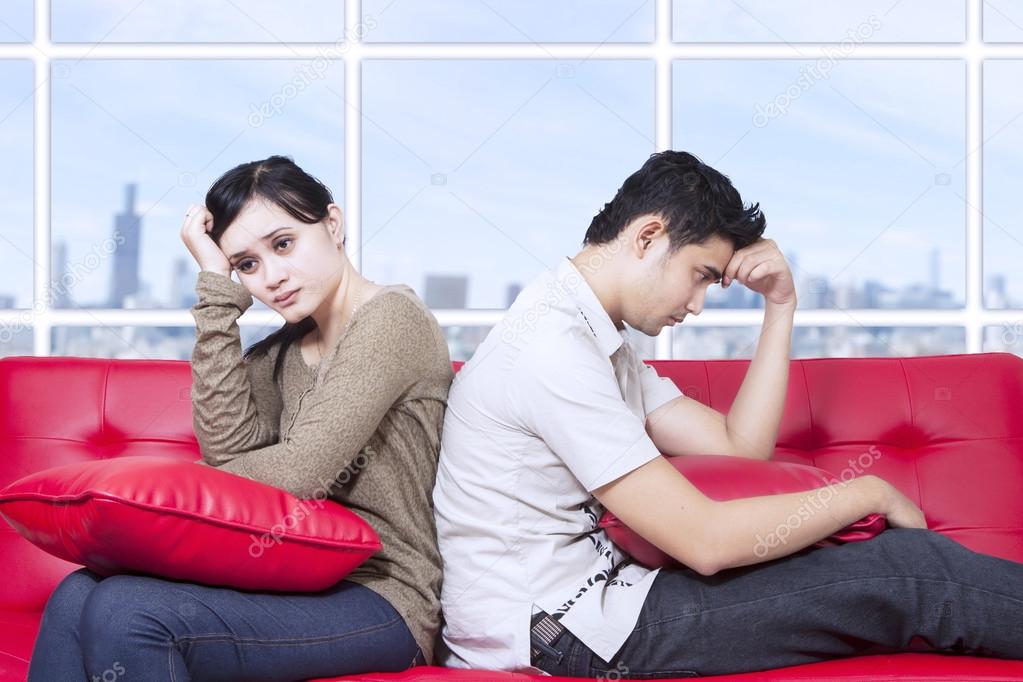 Couple stress sitting on red sofa