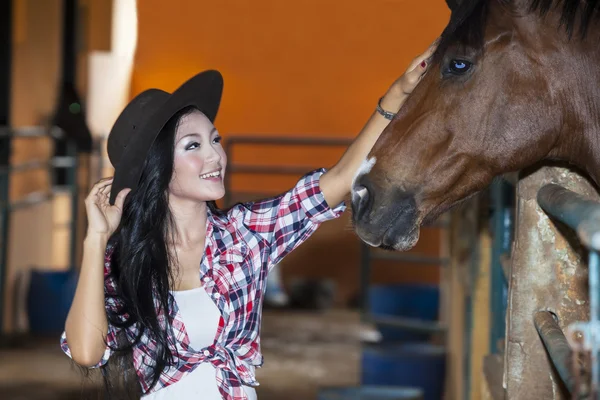 Азиатка трогает лошадь — стоковое фото
