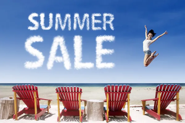 Advertising summer sale jump over beach chairs — Stock Photo, Image