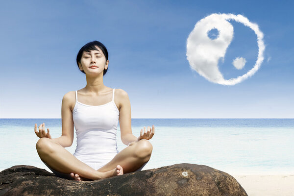 Asian woman meditate under yin yang cloud
