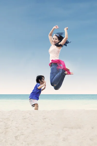 Mère asiatique sautant avec sa fille à la plage — Photo