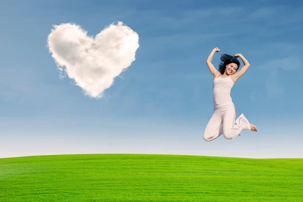 Asian girl jumping on green field — Stock Photo, Image