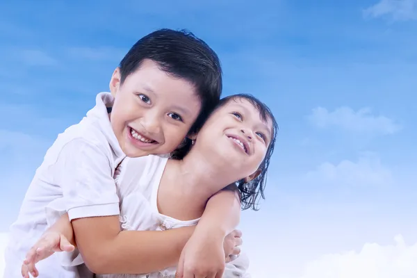 Irmão bonito e irmã sob o céu azul — Fotografia de Stock