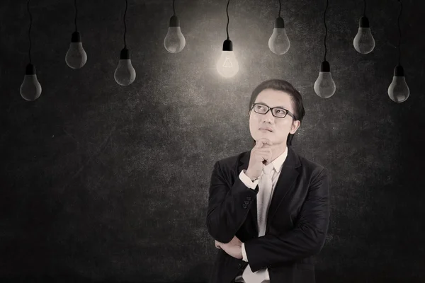 Businessman looking at lit lightbulb — Stock Photo, Image