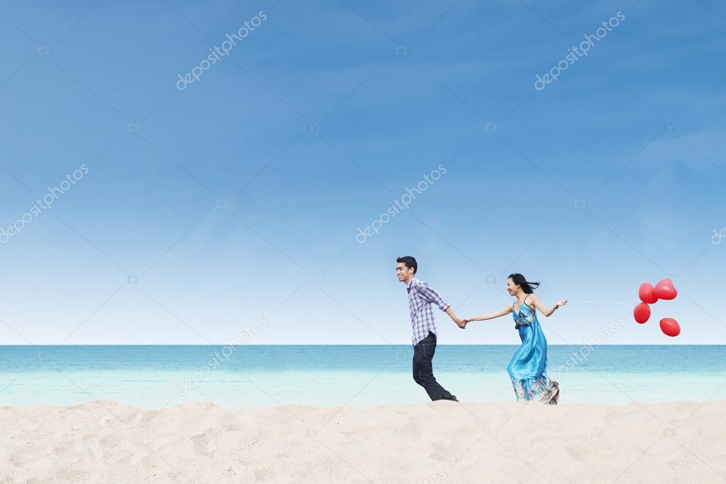 Running couple at beach wih balloons