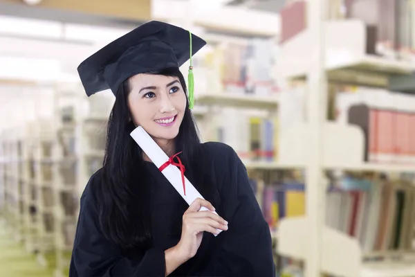 Asiatiska graduate bär gradering klänning på bibliotek — Stockfoto