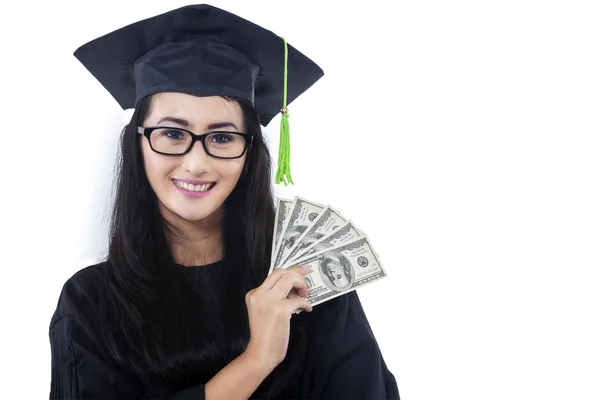 Attractive woman in graduation gown holding money — Stock Photo, Image