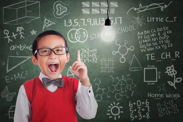 Asian boy has idea under lit bulb in classroom — Stock Photo, Image