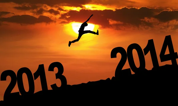 Silhueta incrível de homem pulando ao pôr do sol em direção a 2014 — Fotografia de Stock