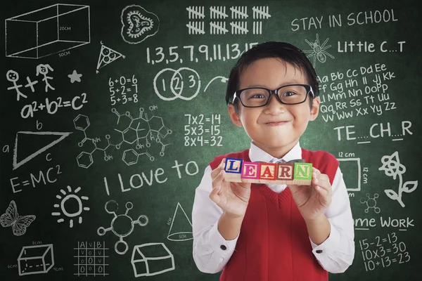 Rapaz sorrindo segurar aprender palavras cruzadas na classe — Fotografia de Stock