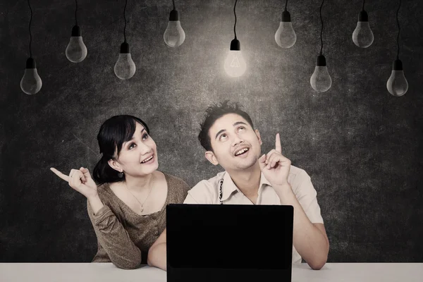 Pareja mirando bombilla en pizarra — Foto de Stock