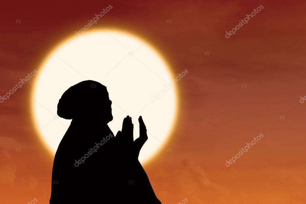 Silhouette of female muslim pray at sunset