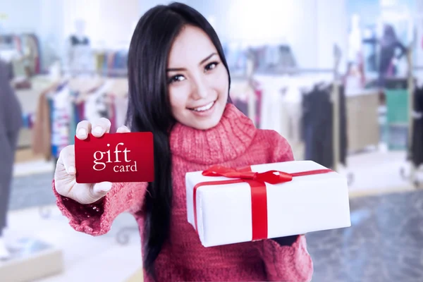 Aantrekkelijke vrouwelijke shopper Toon gift card en vak — Stockfoto