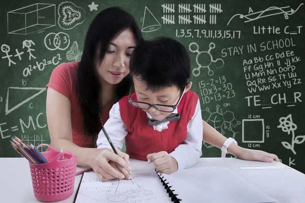çekici öğretmen sınıfta yazmak için bir çocuk yardım