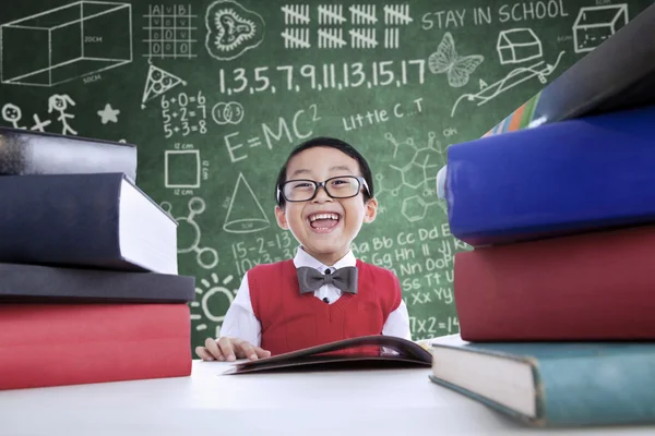 Asiático menino rindo em classe com pilha de livros — Fotografia de Stock