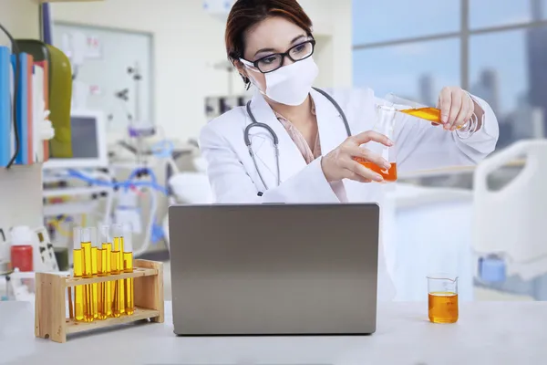 Aziatische vrouwelijke arts analyseren vloeistof bij kliniek — Stockfoto