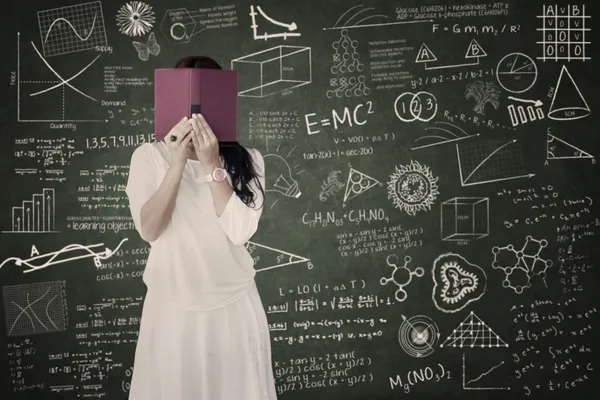 Afraid female student hide behind book in class — Stock Photo, Image