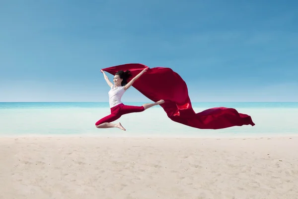 Hermosa bailarina con bandera roja en la playa — Foto de Stock