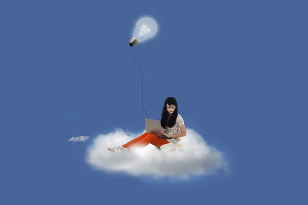 Schöne Frau mit Laptop auf Wolke unter Glühbirne — Stockfoto