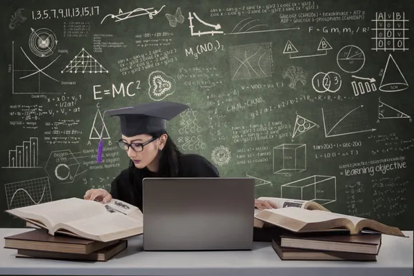 Ocupada graduada leyendo libros en clase — Foto de Stock