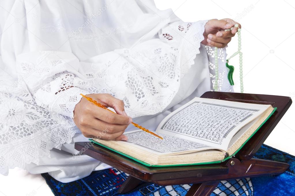 Close-up female muslim reading Quran on white