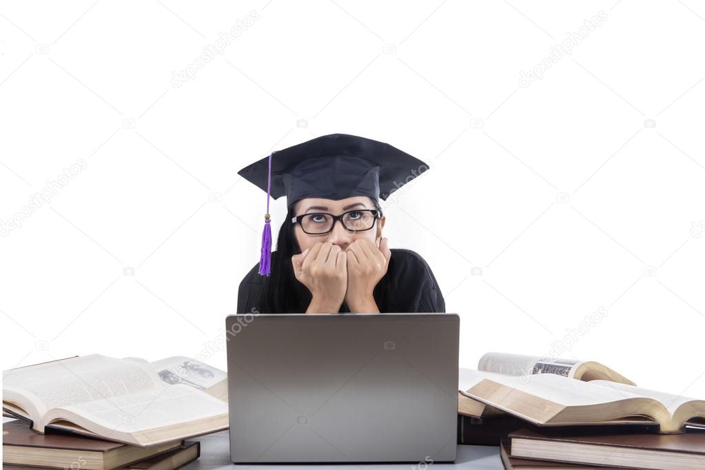Beautiful graduate afraid in front of laptop