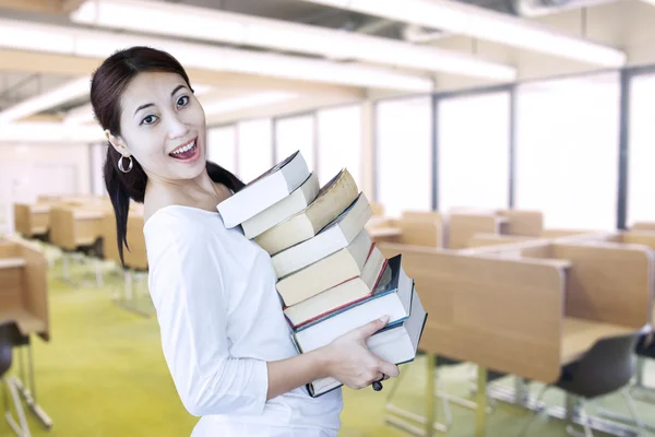 Aantrekkelijke vrouwelijke student brengen stapel boeken in bibliotheek — Stockfoto