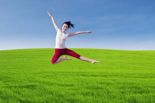 Bella ballerina che salta sopra il campo verde — Foto Stock