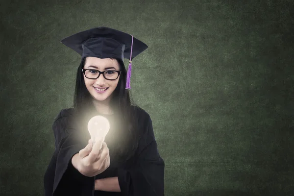 Aantrekkelijke vrouwelijke afgestudeerde geven verlicht lamp in klasse — Stockfoto