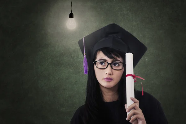 Attractive female graduate with certificate and lit bulb — Stock Photo, Image