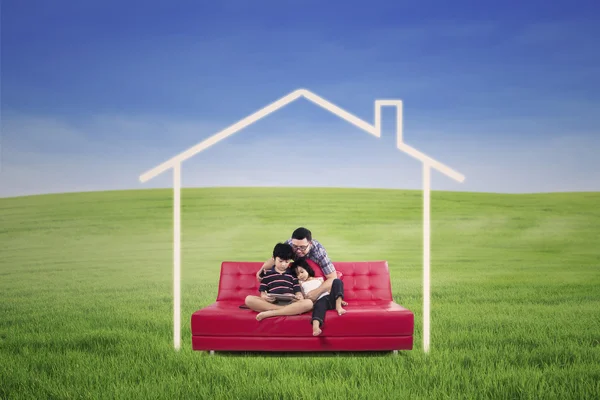 Jovem família sentada em um sofá sonhando uma casa na natureza — Fotografia de Stock