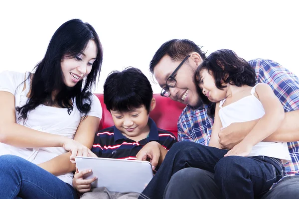 Family using touchpad on red sofa - isolated — Stock Photo, Image