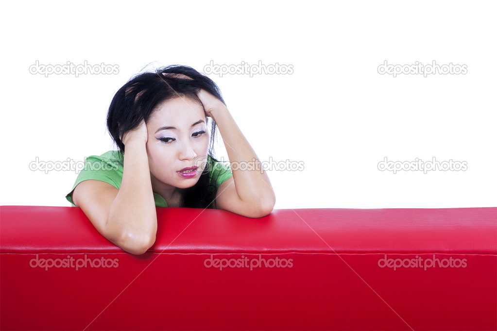 Close-up depressed female on red sofa - isolated