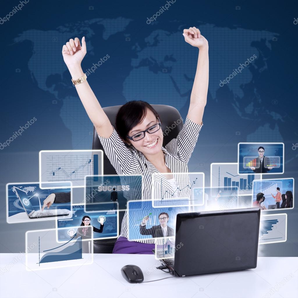 Happy businesswoman raised arms with online pictures at laptop