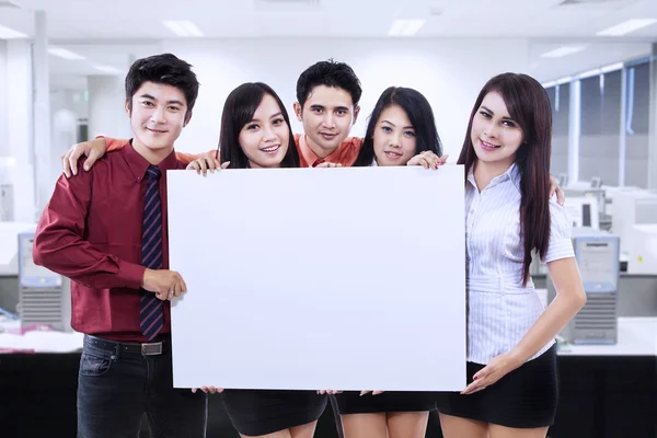 Equipe de negócios segurando quadro branco em branco no escritório — Fotografia de Stock