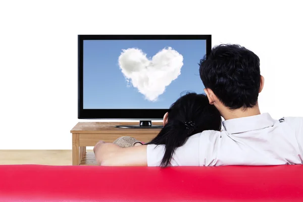 Casal no sofá vermelho assistindo nuvem de amor na tv — Fotografia de Stock