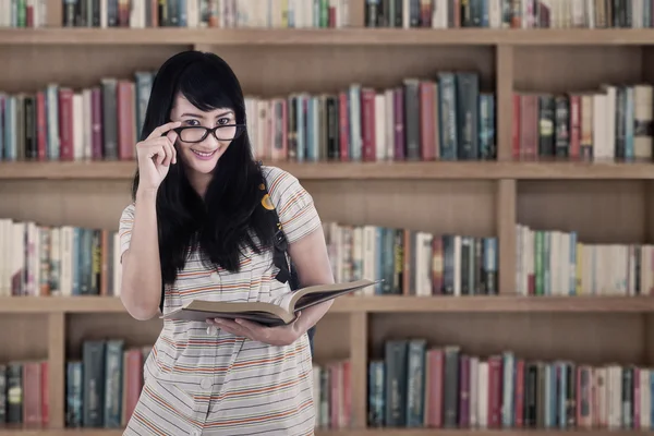 Asiática feminina segurando livro na biblioteca — Fotografia de Stock