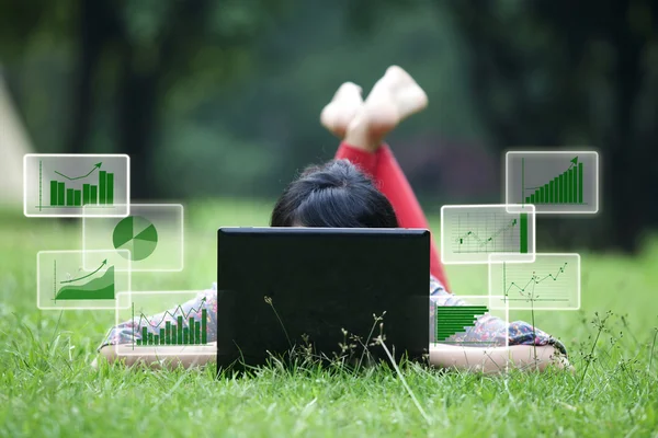 Weibchen liegt mit Laptop und Balkendiagramm im Gras — Stockfoto